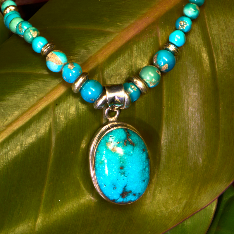 natural turquoise gemstone necklace displayed on green leaves