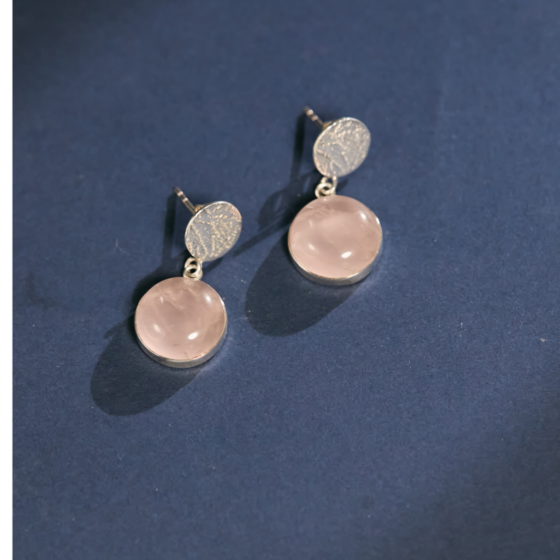 Genuine Detailed view of natural rose quartz bezel-set in high-quality 925 sterling silver. These artisanal drop earrings feature a unique hand-textured finish for a sophisticated look.
