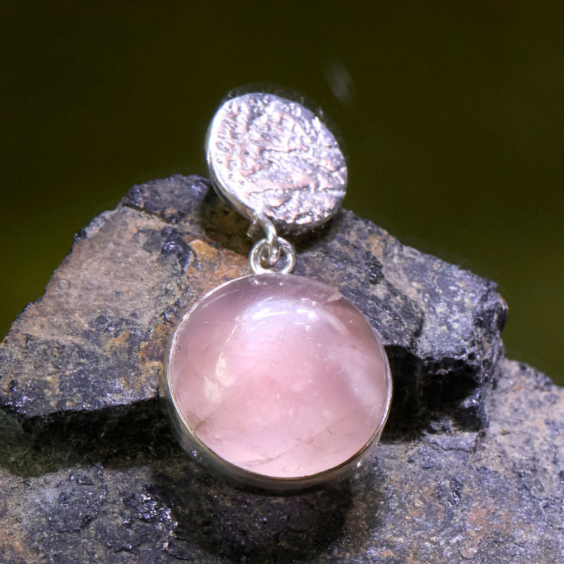 Pink gemstone earring on a dark rock surface