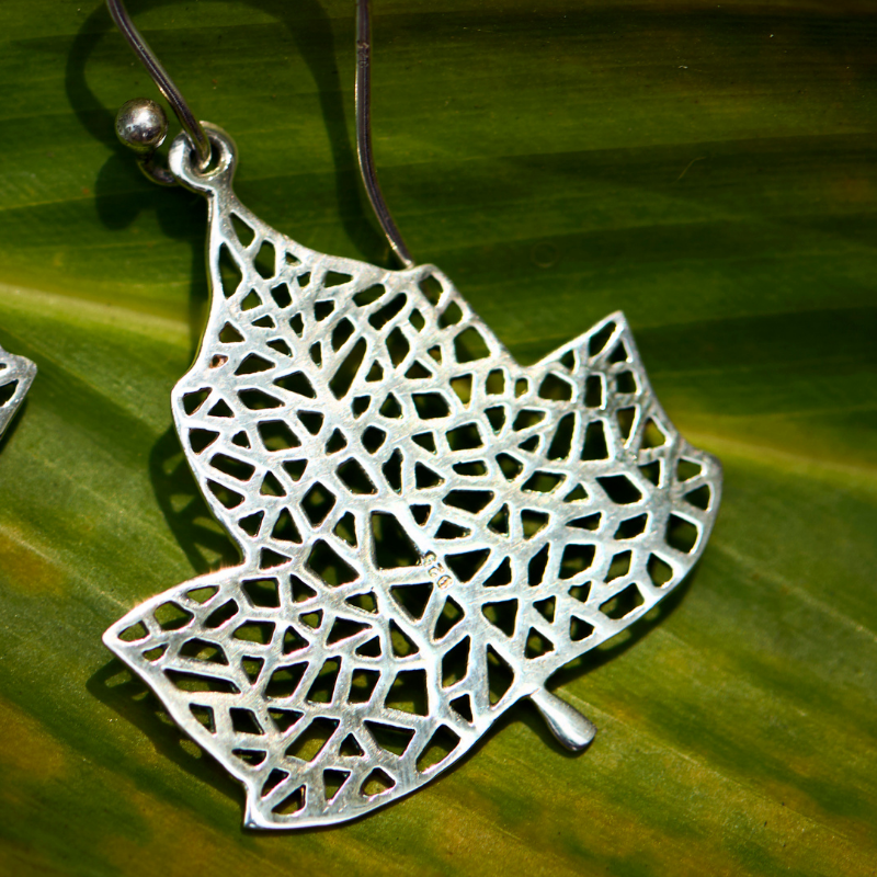 handcrafted sterling silver leaf drop earrings on green leaf