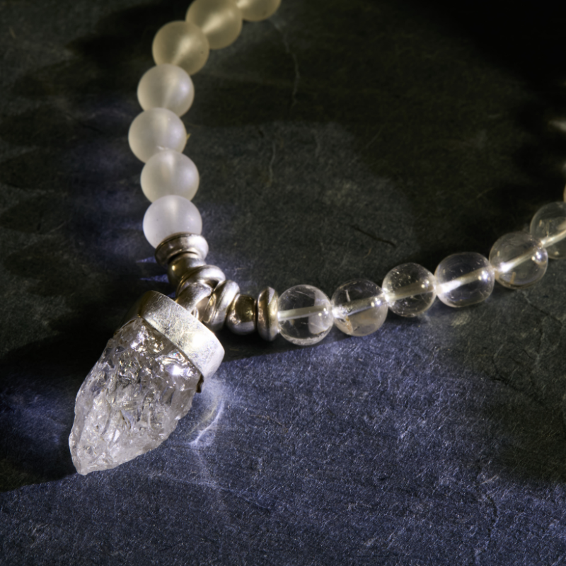 Bespoke, hand-carved crystal arrowhead pendant set in a high-polish 925 sterling silver hallmarked bail, showing the unique raw crystal texture and the intricate silver work.