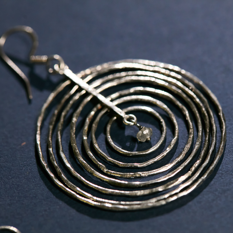 Close-up detail of the hand-hammered texture on solid 925 silver orbital earrings, showing the artisanal craftsmanship and raw gemstone center.