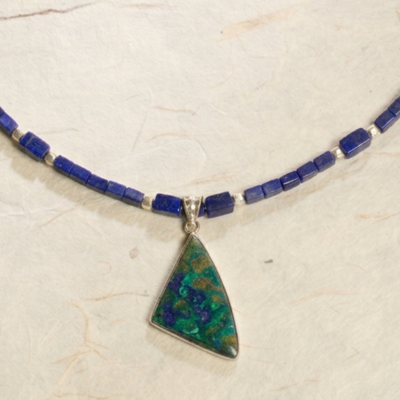 Detailed macro shot of a triangular Malachite and Azurite gemstone pendant showing intricate natural patterns and silver setting.