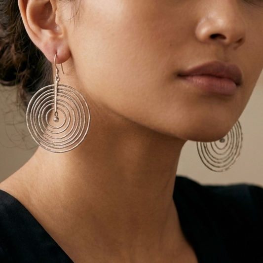 A model wearing the Celestial Orbit 925 silver statement earrings to show the large scale and elegant drape of the concentric hoop design.